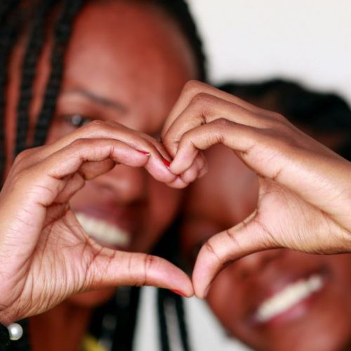 Two women making a heart shape with their hands